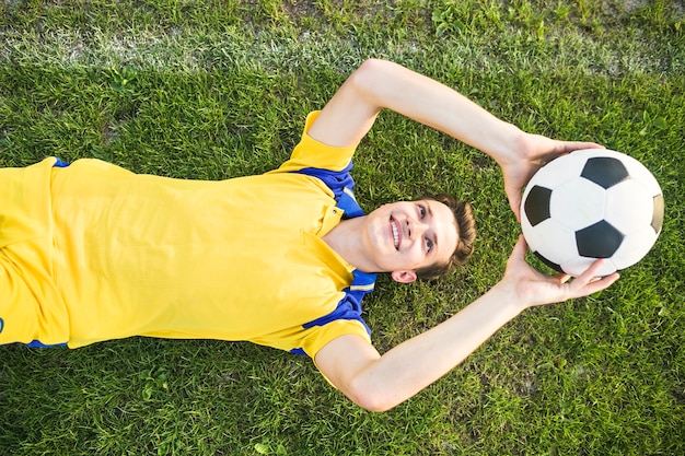 Concepto de fútbol de amateur con hombre tumbada tirando pelota