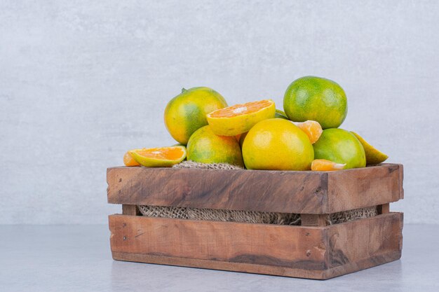 Una canasta de madera llena de mandarinas en rodajas sobre fondo blanco. Foto de alta calidad
