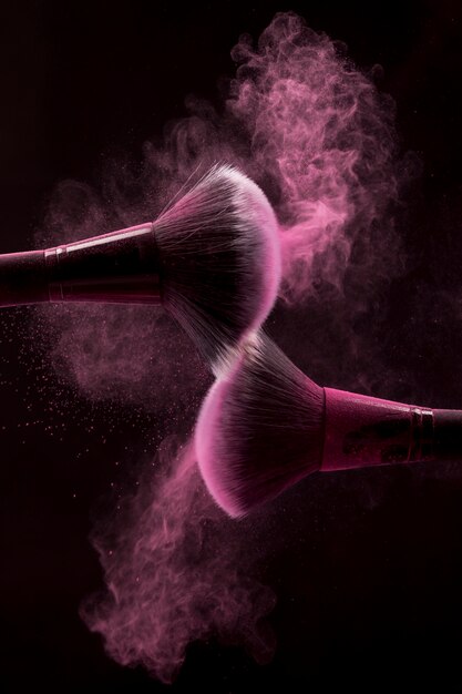 Cepillos cosméticos en niebla rosa de polvo sobre fondo oscuro