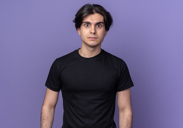 Foto gratuita chico guapo joven sorprendido con camiseta negra aislada en la pared púrpura