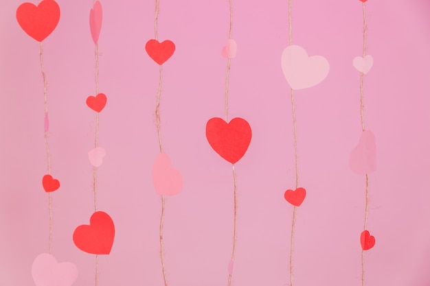 Foto gratuita cuerdas compuestas por corazones en un fondo rosa