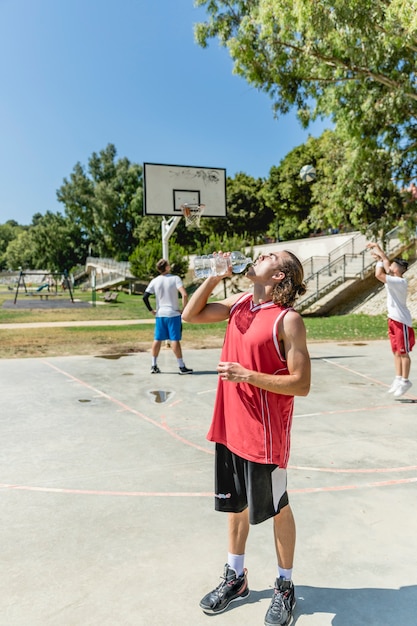 Foto gratuita agua potable de jugador de baloncesto de la botella en la cancha al aire libre