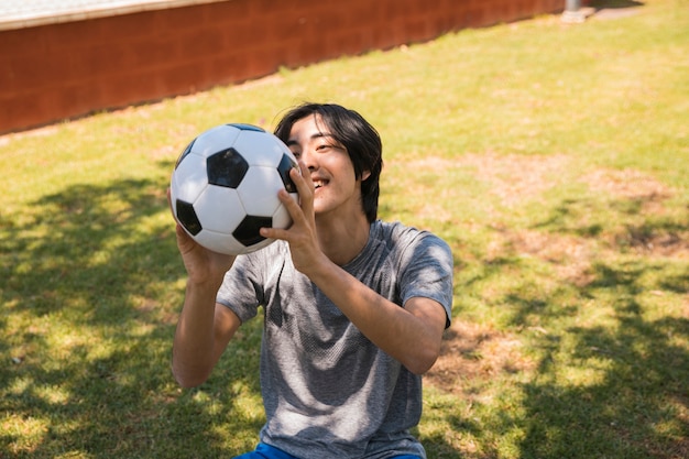 Foto gratuita alegre estudiante asiático adolescente atrapar pelota de fútbol