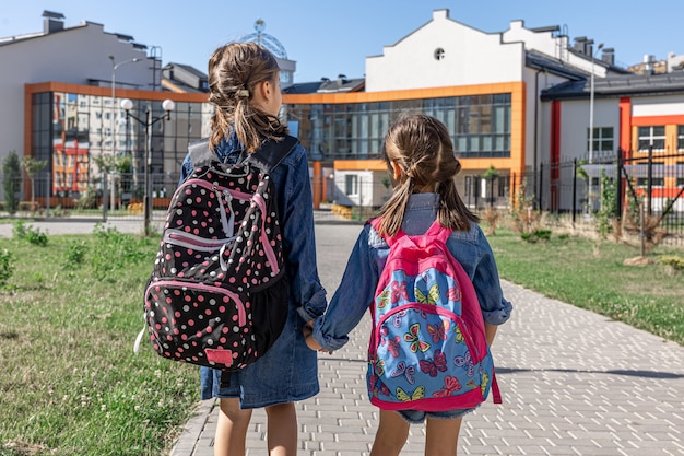 Foto gratuita dos niñas van a la escuela, tomados de la mano, vista posterior.