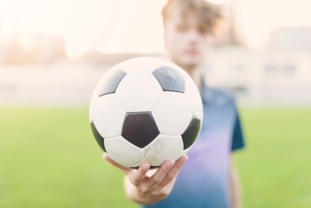 Deportista borrosa mostrando el balón de fútbol