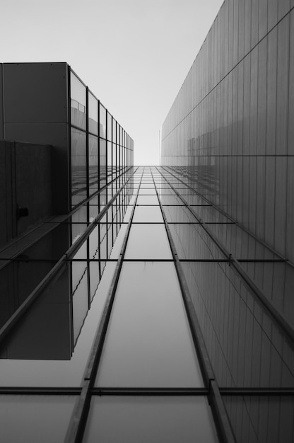 Foto gratuita escala de grises de un techo de un edificio moderno con ventanas de vidrio bajo la luz del sol