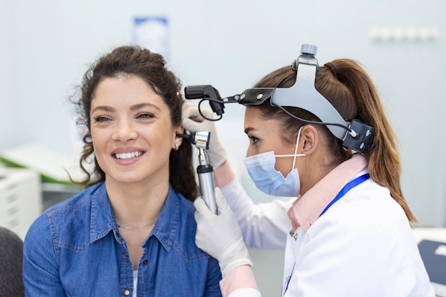 Foto gratuita examen de audición médico otorrinolaringólogo revisando el oído de la mujer usando otoscopio o auriscopio en la clínica médica