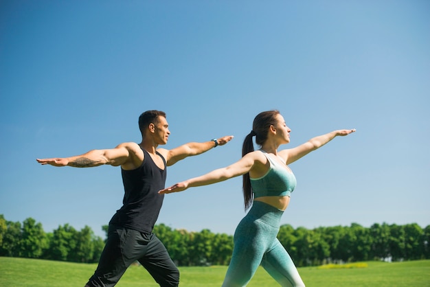 Foto gratuita hombre y mujer practicando yoga al aire libre