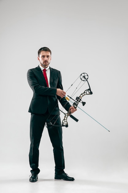 Foto gratuita hombre de negocios con el objetivo de objetivo con arco y flecha, aislado sobre fondo gris de estudio.