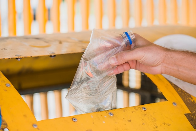 Foto gratuita hombre lanzando botella de plástico en papelera de reciclaje