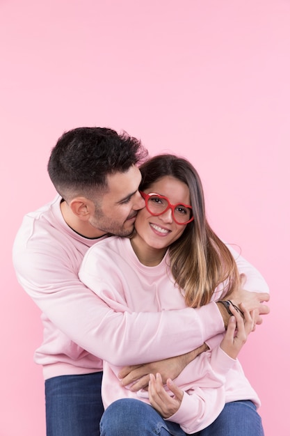 Foto gratuita hombre que abraza a la mujer atractiva alegre con las lentes