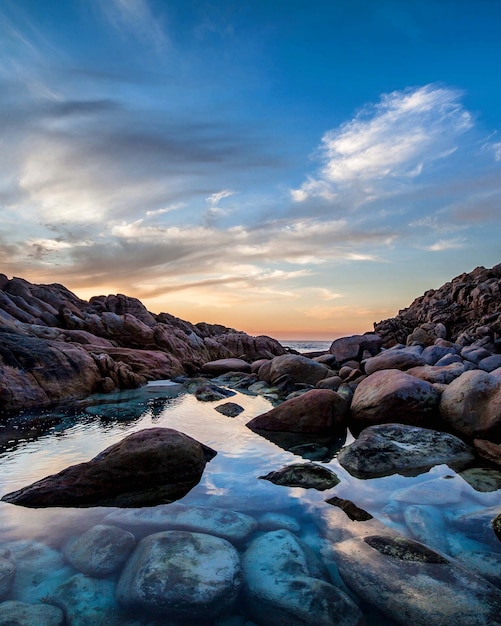 Foto gratuita hermosa puesta de sol en la playa con rocas