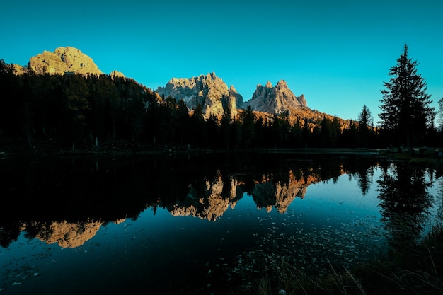 Foto gratuita hermoso tiro de agua que refleja los árboles y las montañas con cielo azul