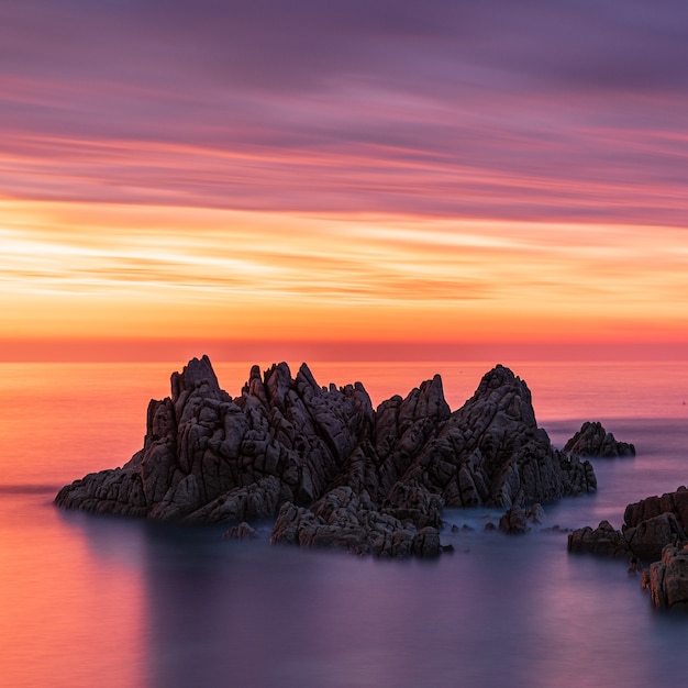 Foto gratuita impresionante paisaje de pilas de mar durante la puesta de sol bajo el colorido cielo en guernsey