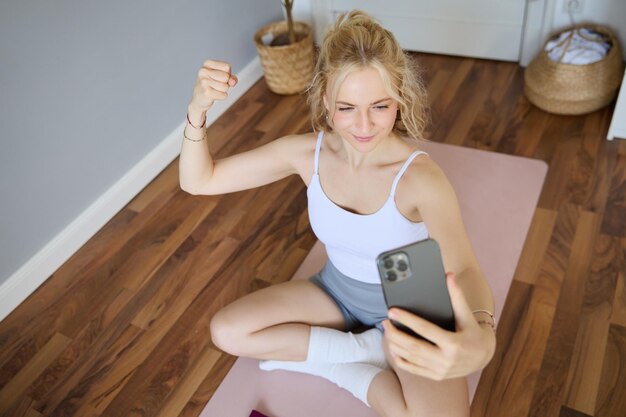 Foto gratuita joven entrenador de fitness deportivo instructor de yoga hace transmisión en vivo toma selfies en el teléfono inteligente mientras