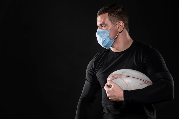 Jugador de rugby masculino con máscara médica y espacio de copia