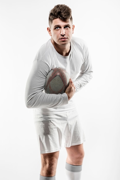 Jugador de rugby masculino posando con pelota