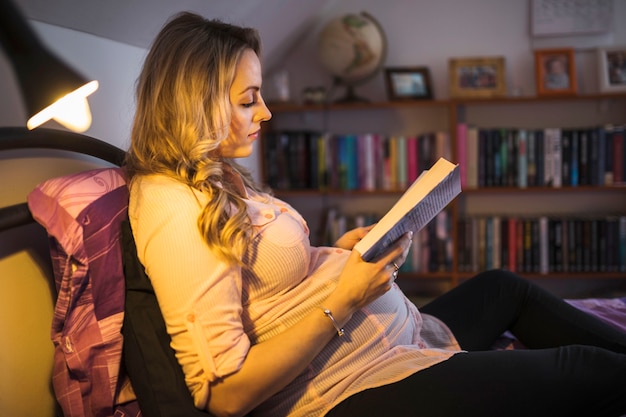 Foto gratuita libro de lectura de mujer embarazada en la noche