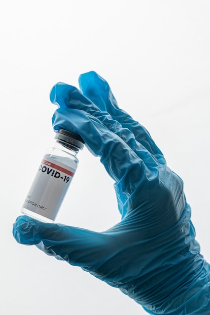 Foto gratuita mano con guante con vial de vacuna