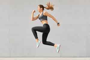 Foto gratuita mujer activa llena de energía, salta en el aire, usa ropa deportiva, se prepara para competiciones deportivas