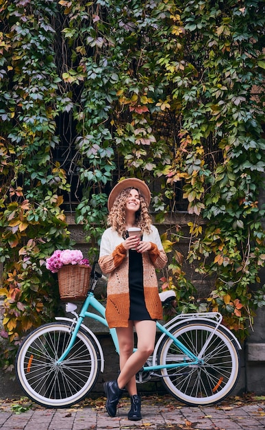 Foto gratuita mujer feliz parada cerca de una bicicleta antigua en el parque de la ciudad