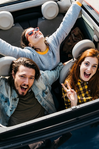 Foto gratuita mujeres sonrientes y hombre positivo sentado en coche