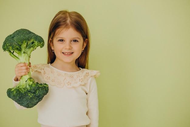 Foto gratuita niña aislada sosteniendo brócoli crudo verde