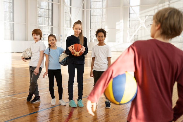 Foto gratuita niños deportivos sosteniendo pelotas en el gimnasio