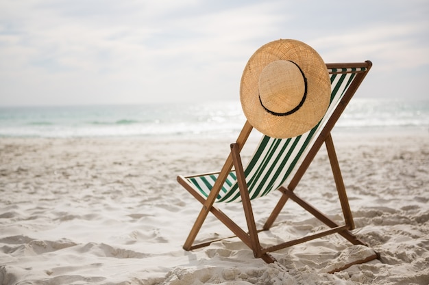 Foto gratuita sombrero de paja mantuvo en silla de playa vacía