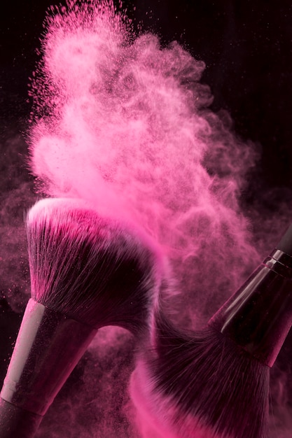 Foto gratuita polvo rosa extendido con pinceles frotándose entre sí.
