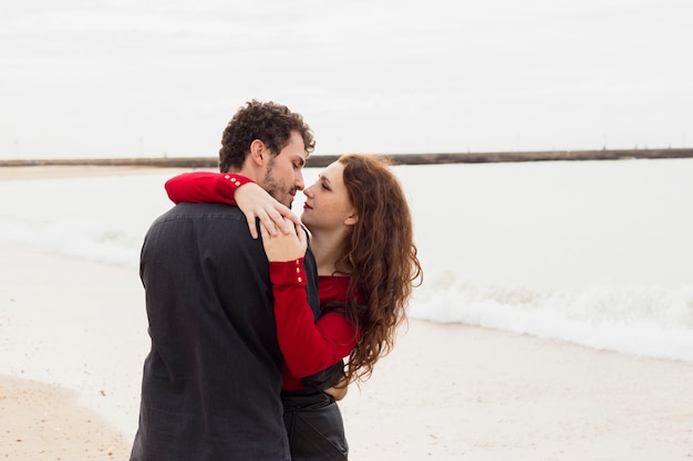 Foto gratuita pareja joven, abrazar, en, orilla de mar