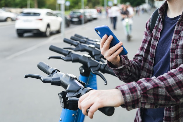 Foto gratuita primer plano de la mano del hombre usando la aplicación móvil para alquilar scooter eléctrico