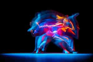 Foto gratuita retrato dinámico de un joven y una mujer bailando hiphop aislado sobre fondo negro con efecto de luces mixtas