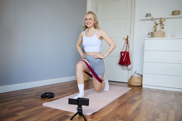 Foto gratuita retrato de instructora de fitness joven vlogger deportiva mujer haciendo ejercicios en la cámara de rodaje de video