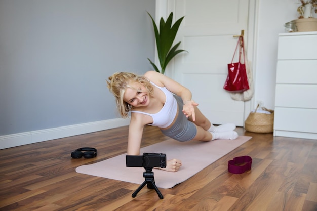 Foto gratuita retrato de una joven vlogger instructora de fitness en forma y sana de pie en una grabación de tabla lateral