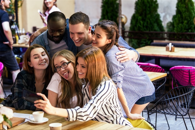 Foto gratuita reunión informal de los mejores amigos en el acogedor café y tomar una foto selfie en el teléfono inteligente