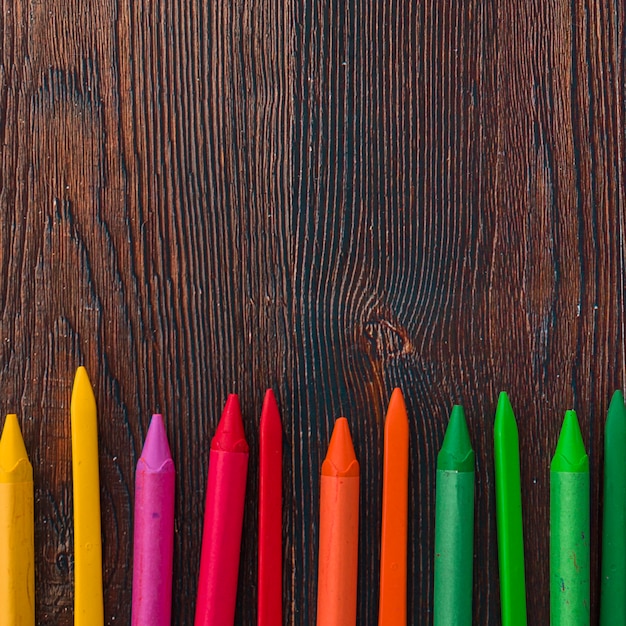 Foto gratuita vista elevada de crayones de cera multicolores en tablón marrón