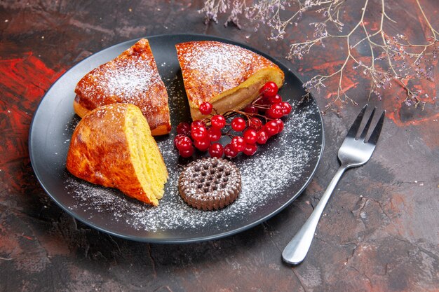 Foto gratuita vista frontal delicioso pastel en rodajas con frutos rojos sobre piso oscuro