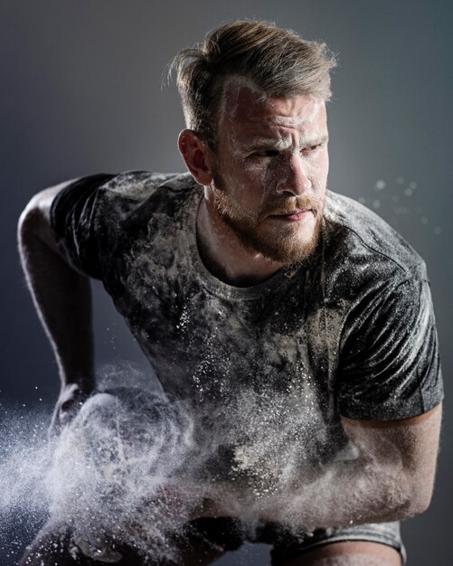 Vista frontal del jugador de rugby masculino atlético sosteniendo la bola con polvo