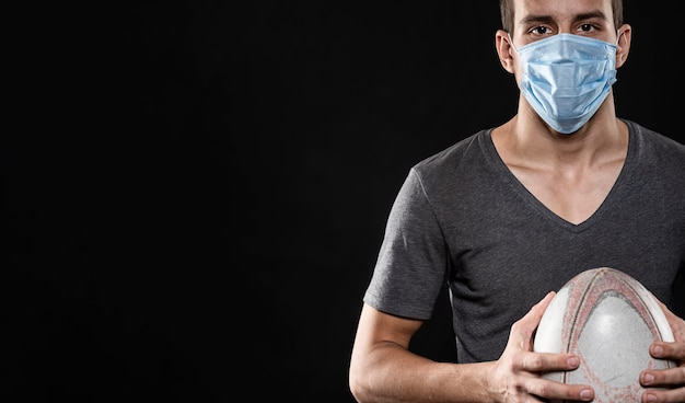 Vista frontal del jugador de rugby masculino con máscara médica y espacio de copia
