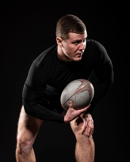 Vista frontal del jugador de rugby masculino sosteniendo la pelota con una mano