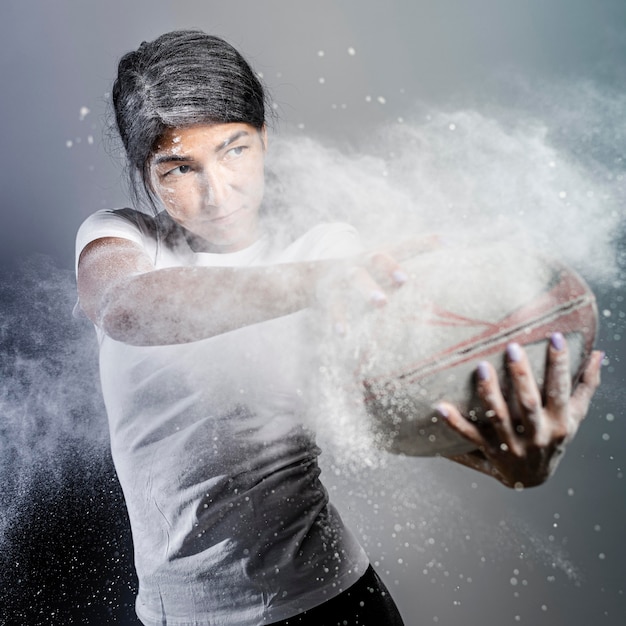 Vista frontal del jugador de rugby femenino atlético sosteniendo la bola con polvo