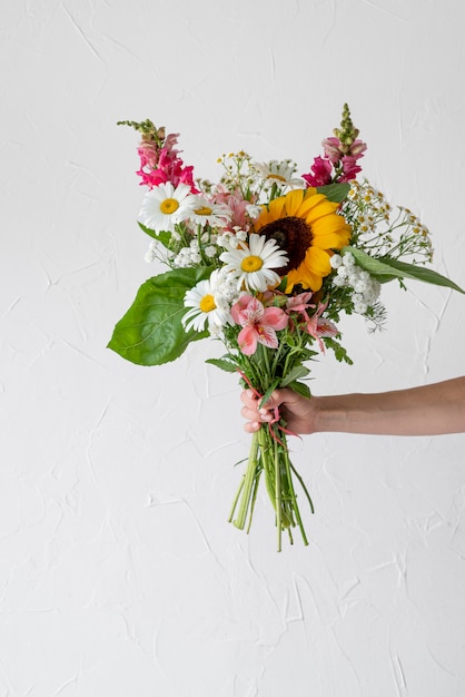 Foto gratuita vista frontal de la mano femenina que sostiene el ramo de flores