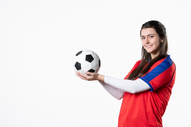 Foto gratuita vista frontal de las mujeres jóvenes en ropa deportiva con balón de fútbol en la pared blanca