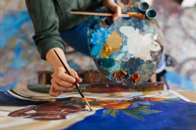 Foto gratuita vista superior de atractivas manos de mujer dibujando una imagen increíble sobre lienzo en un moderno y acogedor taller de arte
