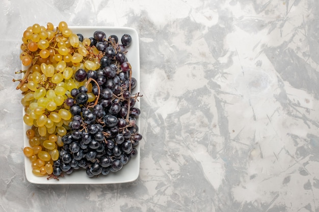 Foto gratuita vista superior de uvas frescas frutas suaves y jugosas dentro de la placa sobre un fondo blanco árbol de jugo de uva de vino fresco de frutas