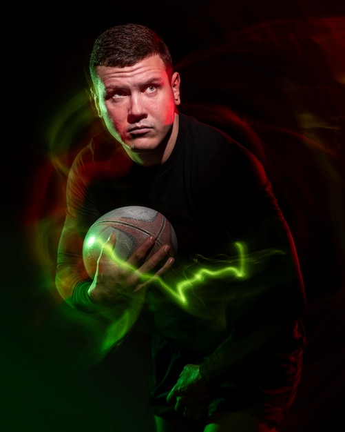 Vista frontale del giocatore di rugby maschile che tiene palla con effetto colore
