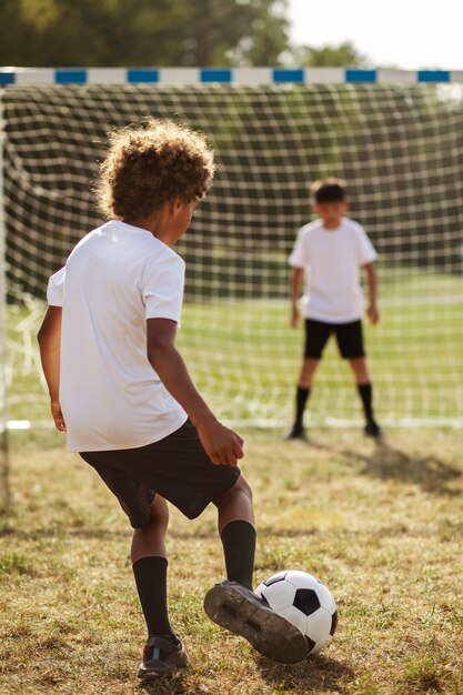 Bambini che giocano a calcio sotto la supervisione di un allenatore di calcio