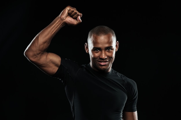 Giovane uomo afroamericano felice di sport che celebra la sua vittoria con il braccio alzato