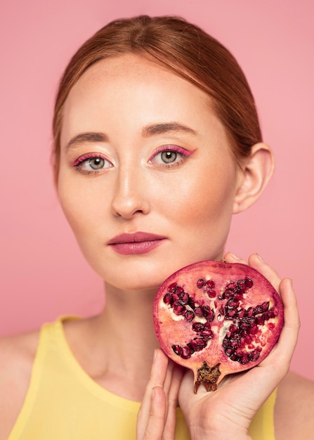 Ritratto di donna bella rossa che tiene un frutto